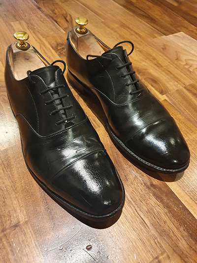 Pair of restored black mens black derby shoes after a shoeshine